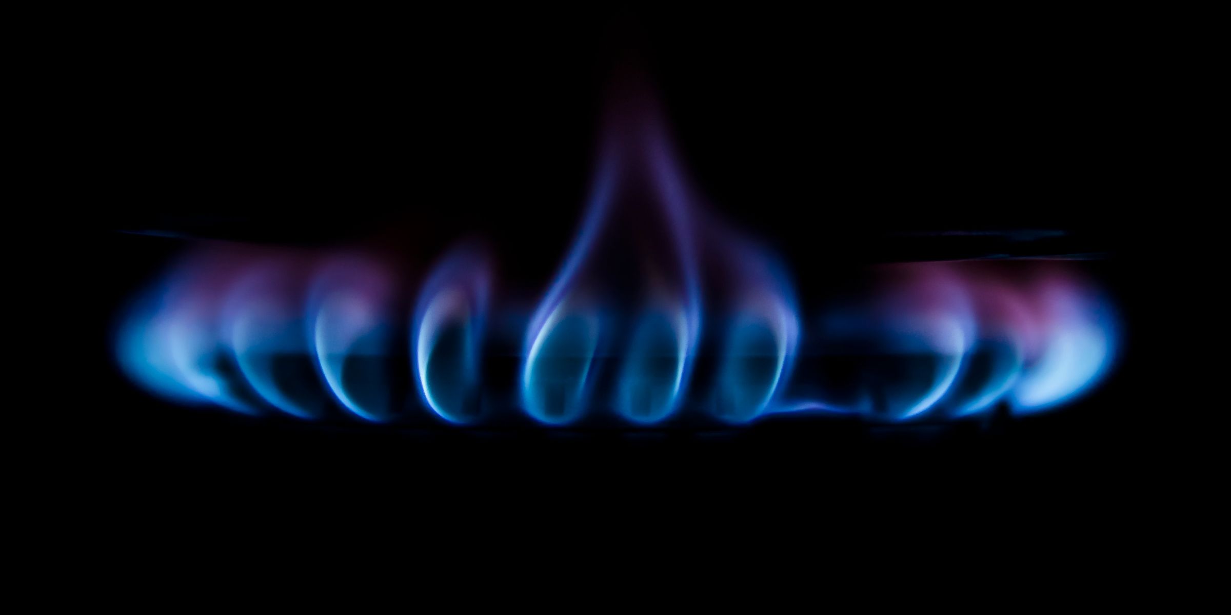 Eine blaue Gasflamme brennt auf dunklem Hintergrund
