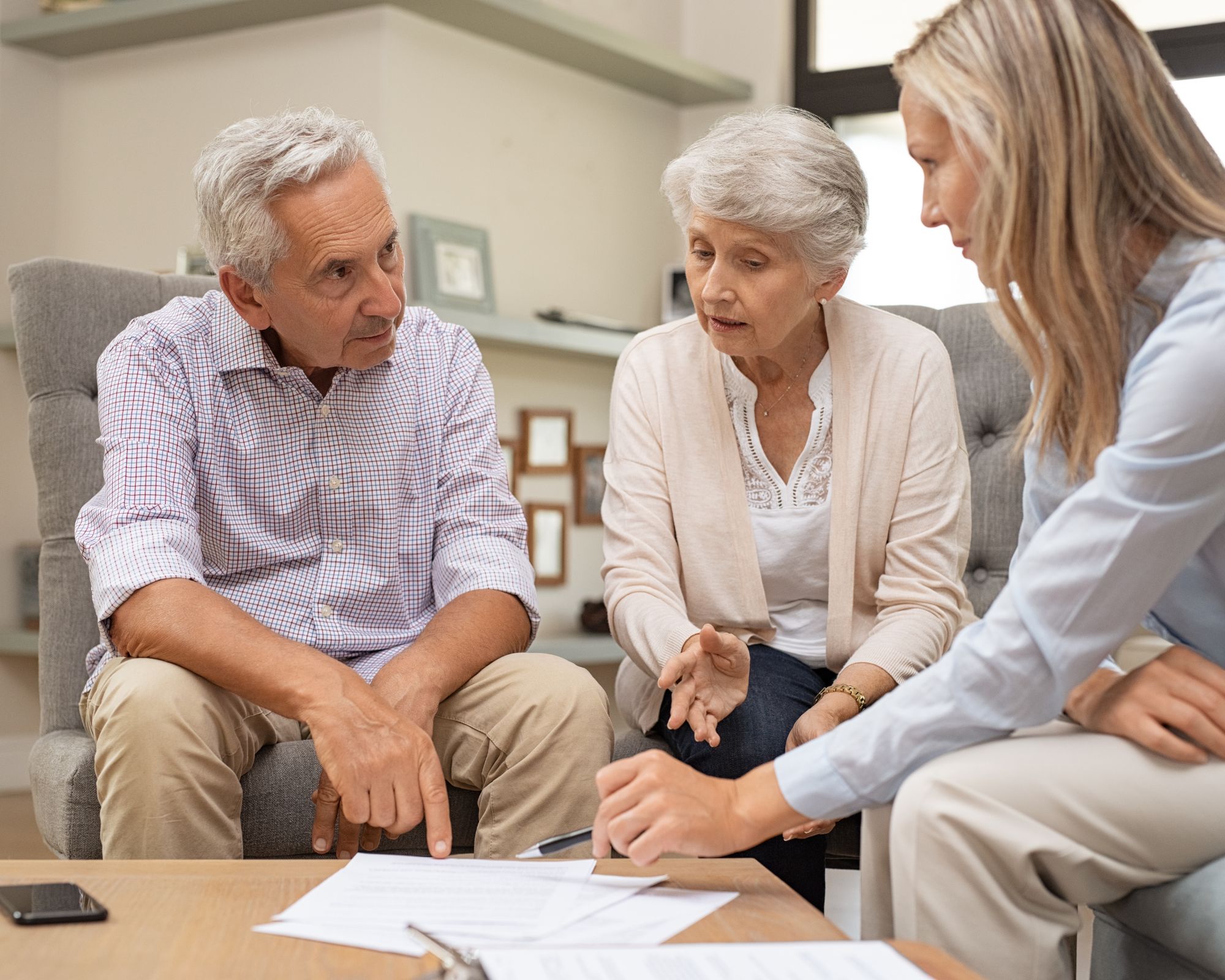 Beratungsgespräch eines älteren Paares mit einer Fachkraft am Tisch