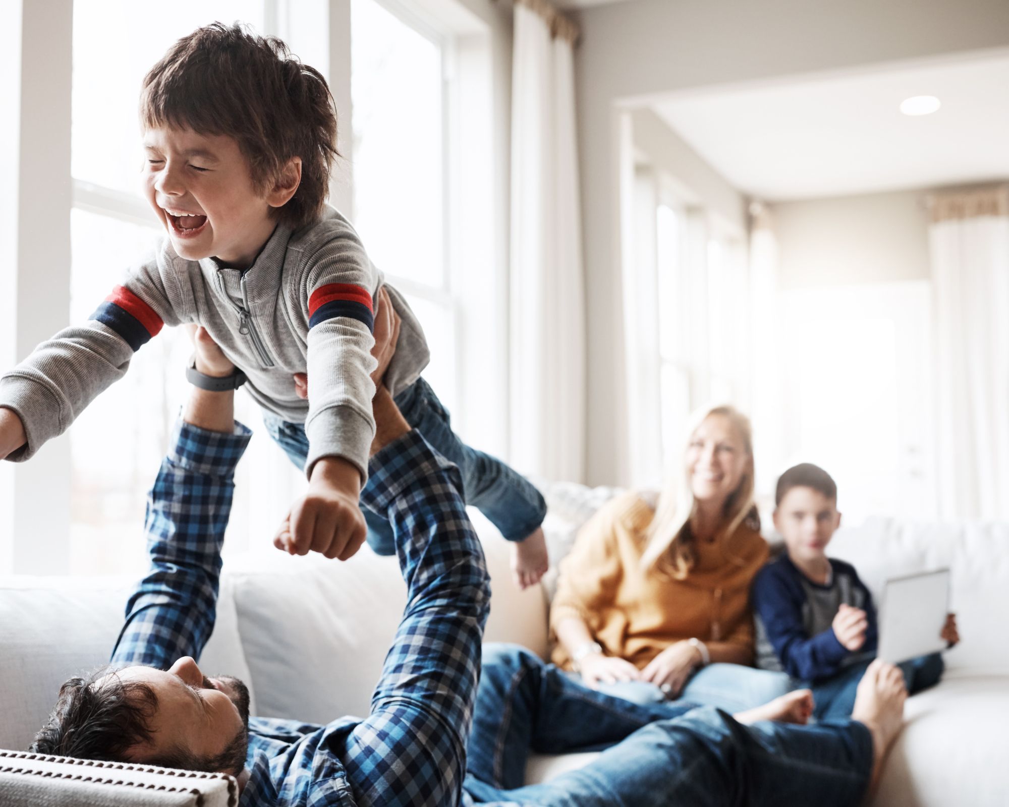 Familie entspannt auf dem Sofa und spielt mit einem Kind