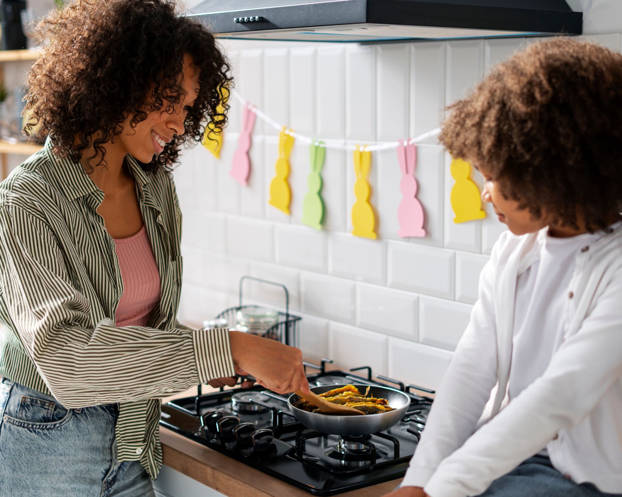 Eine Person kocht, ein Kind sitzt daneben auf der Arbeitsfläche