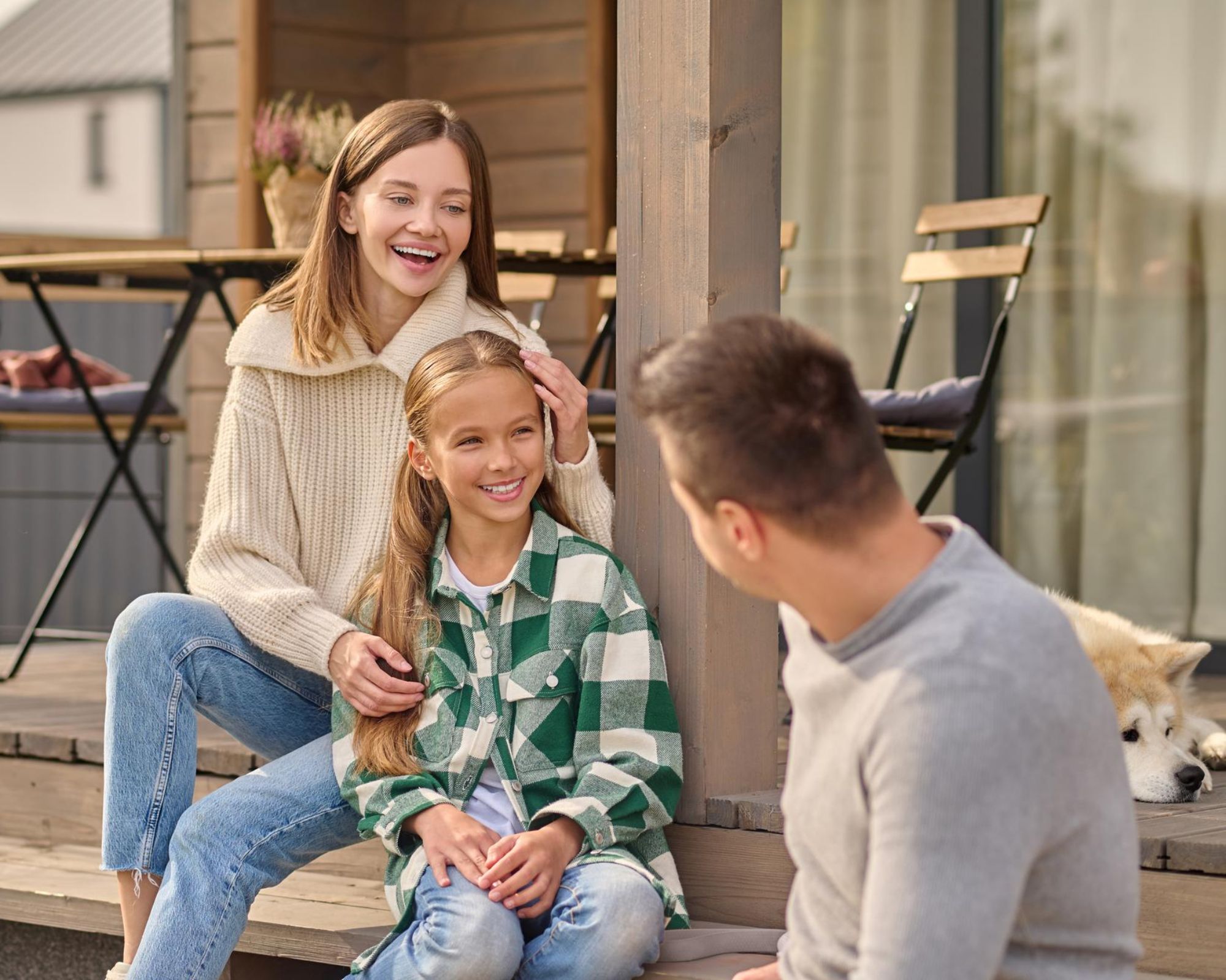 Menschen sitzen gemeinsam auf der Terrasse eines modernen Einfamilienhauses und verbringen Zeit im Außenbereich ihres Zuhauses.